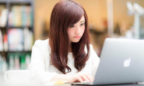 ノートパソコンでブログを書いている若い女性